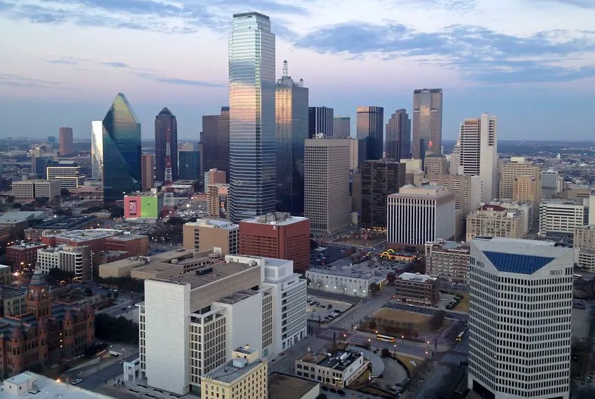 Aerial view of the Dallas skyline at sunset, featuring iconic skyscrapers and city lights